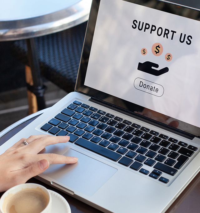 Hand near laptop with donation page