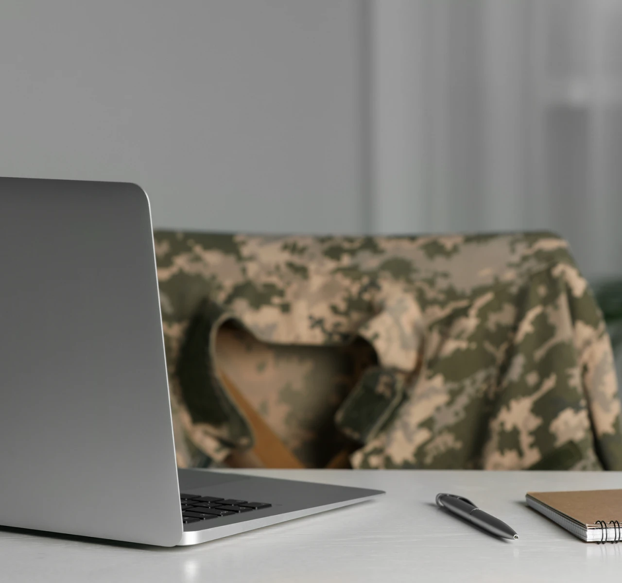 Camouflage jacket behind open laptop